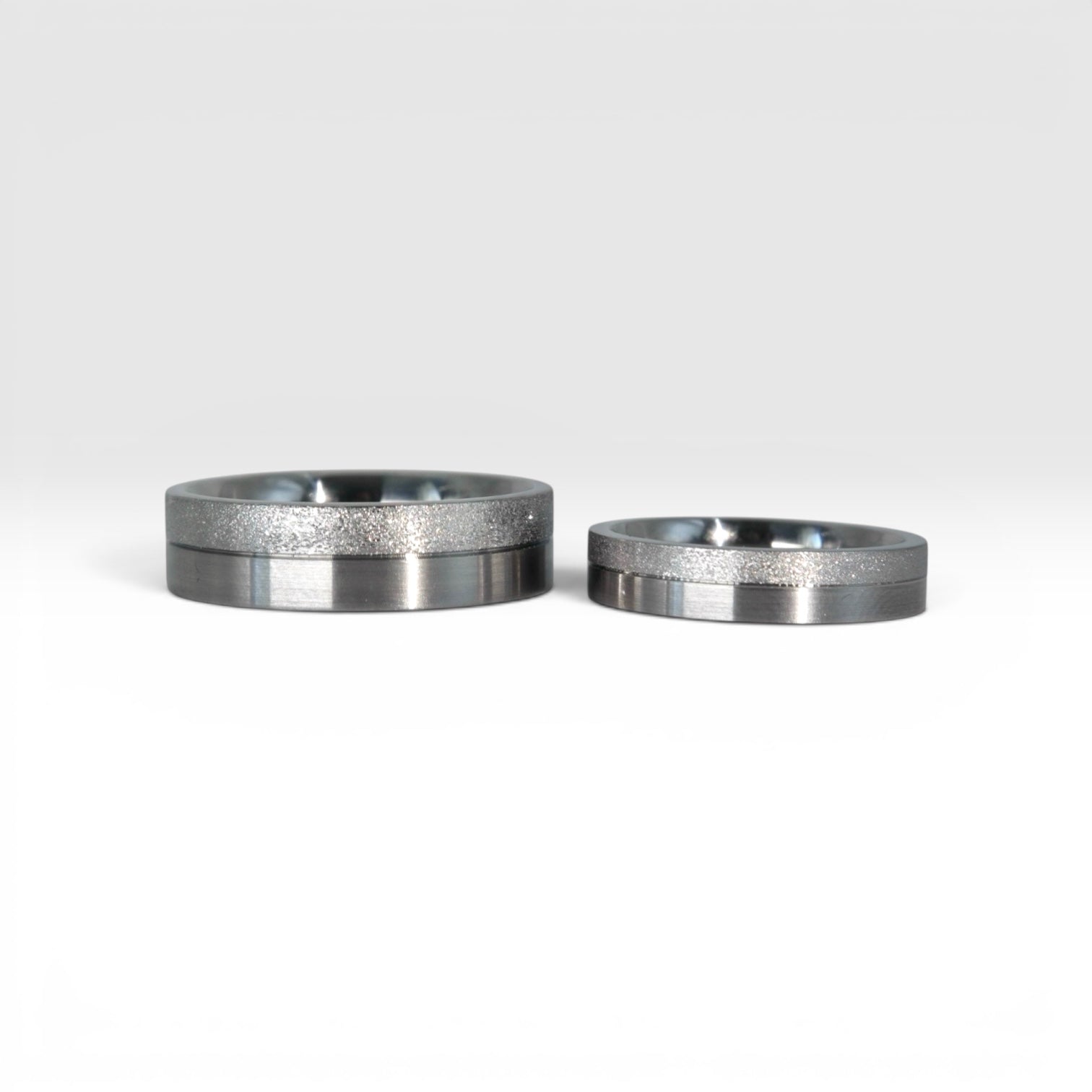 Matching two-tone wedding band set, 6mm his and 4mm hers, with frosted finish top half and satin lower half separated by a precision groove, handcrafted in Utah