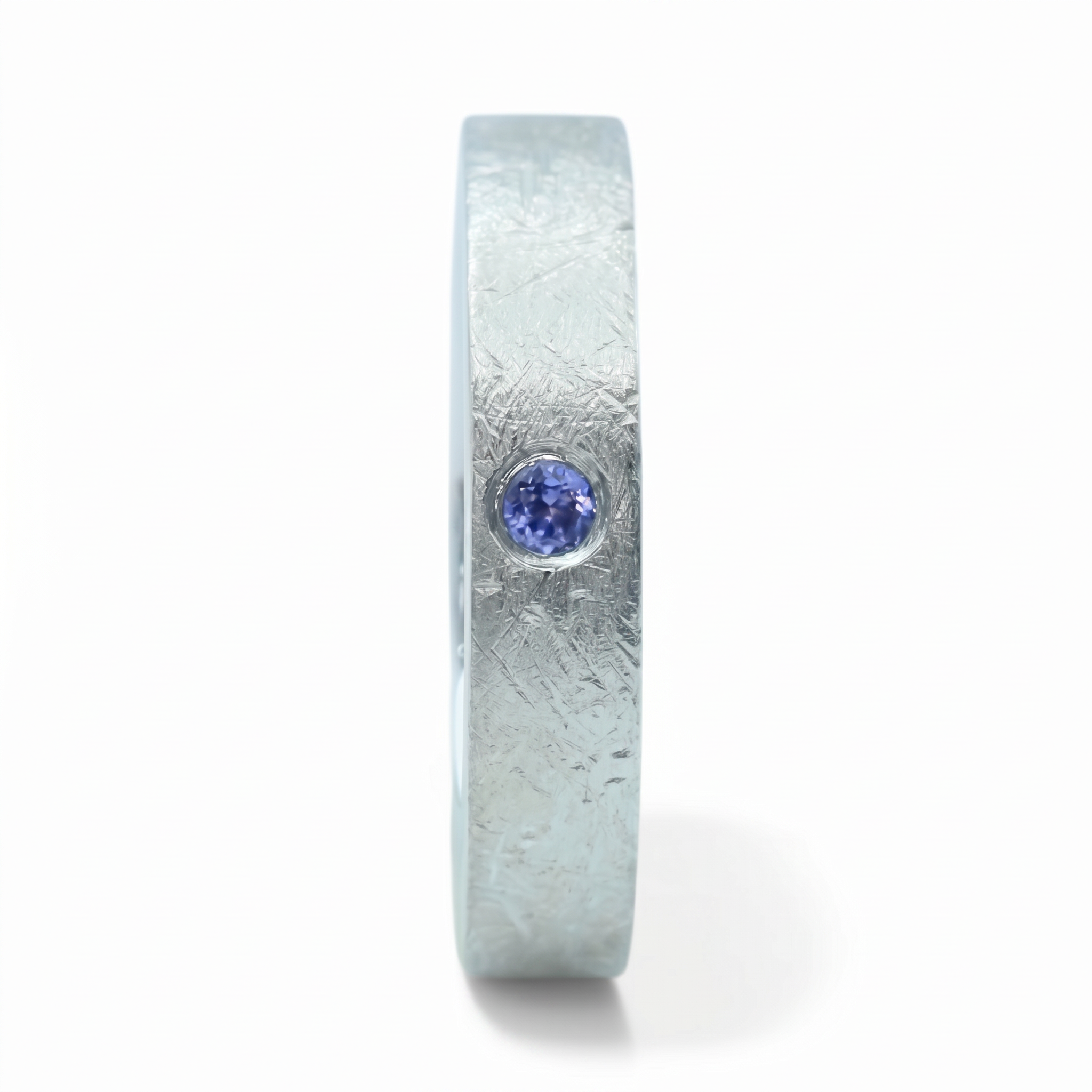 Close-up of sterling silver ring with blue topaz flush set stone and textured surface