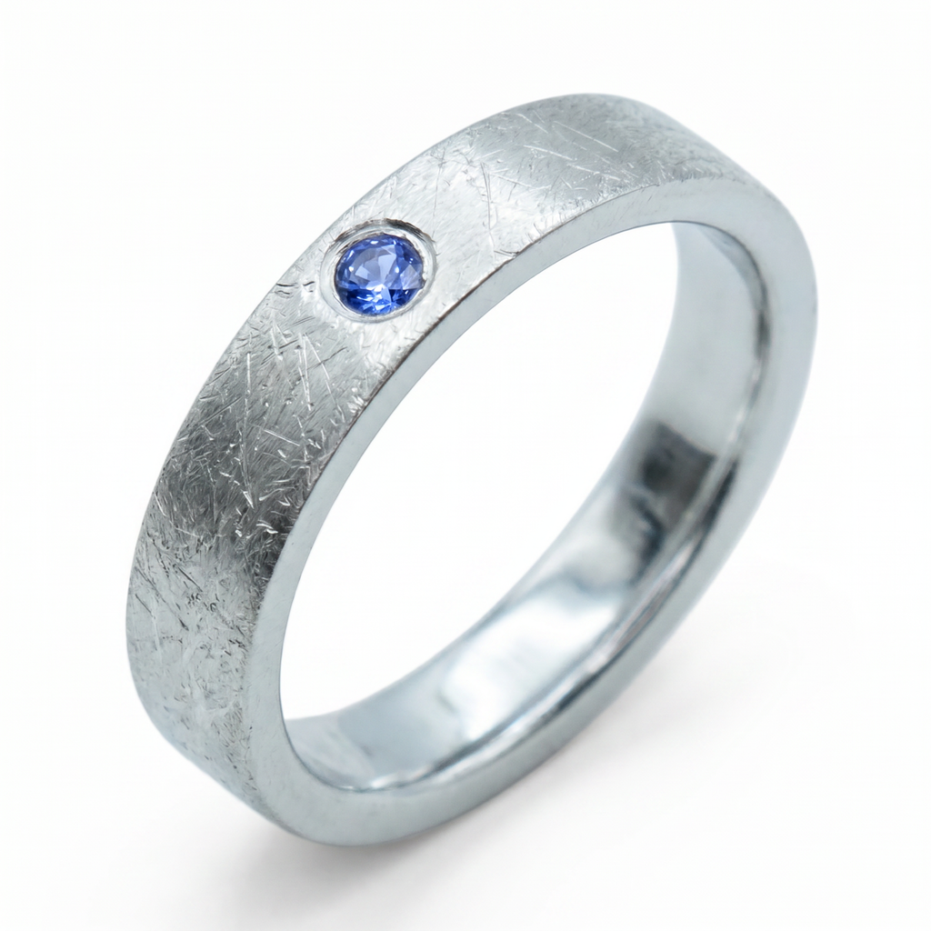 Close-up of sterling silver ring with blue topaz flush set stone and textured surface