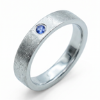 Close-up of sterling silver ring with blue topaz flush set stone and textured surface