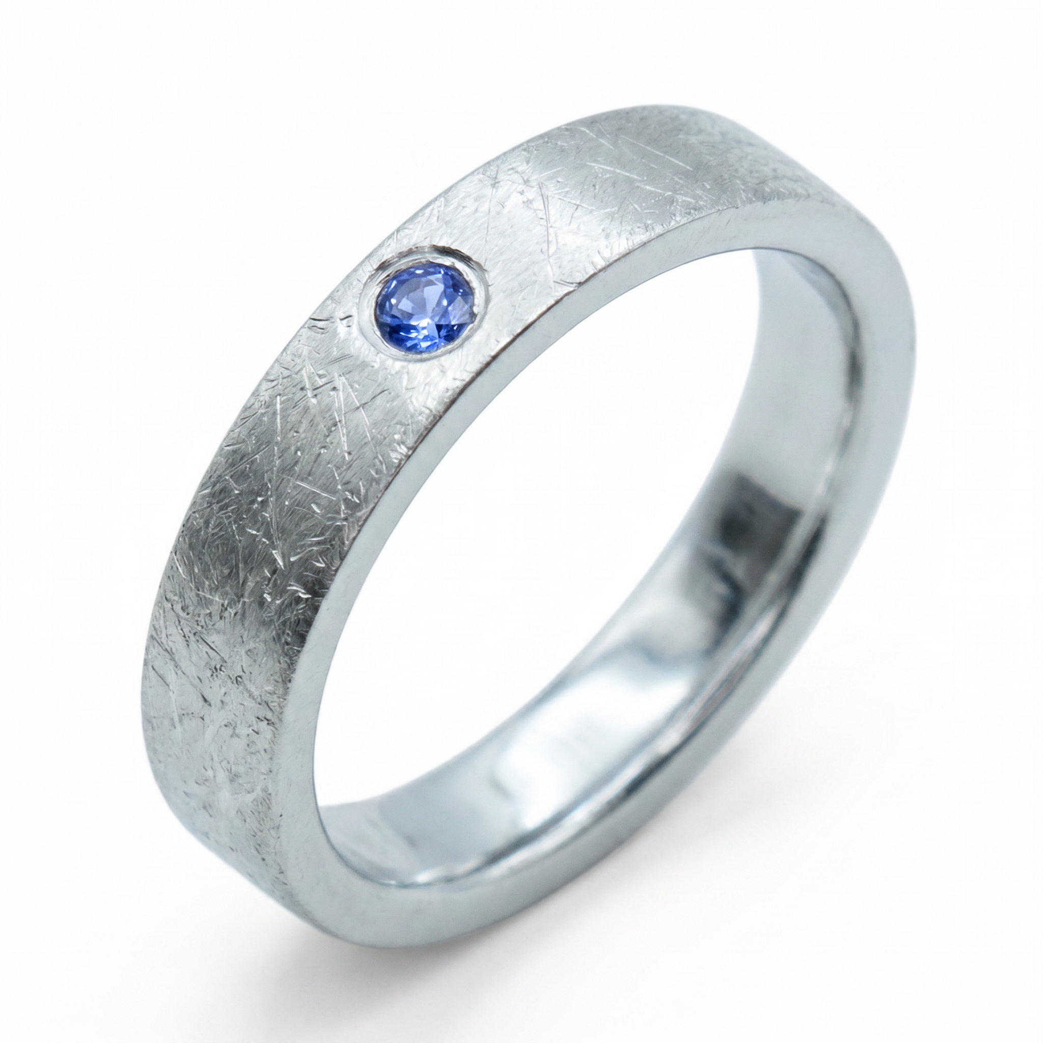 Close-up of sterling silver ring with blue topaz flush set stone and textured surface