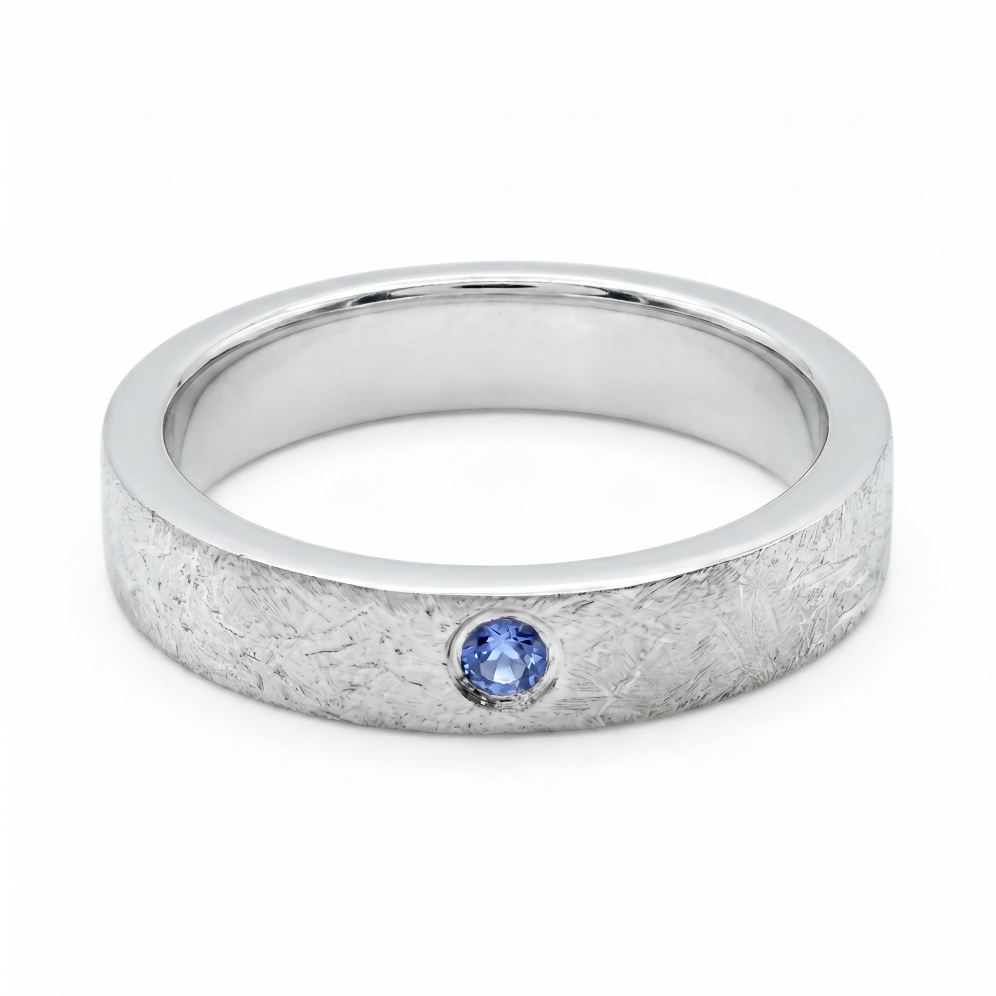 Close-up of sterling silver ring with blue topaz flush set stone and textured surface