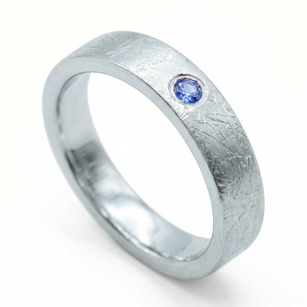 Close-up of sterling silver ring with blue topaz flush set stone and textured surface