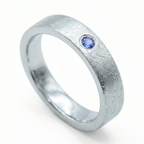 Close-up of sterling silver ring with blue topaz flush set stone and textured surface