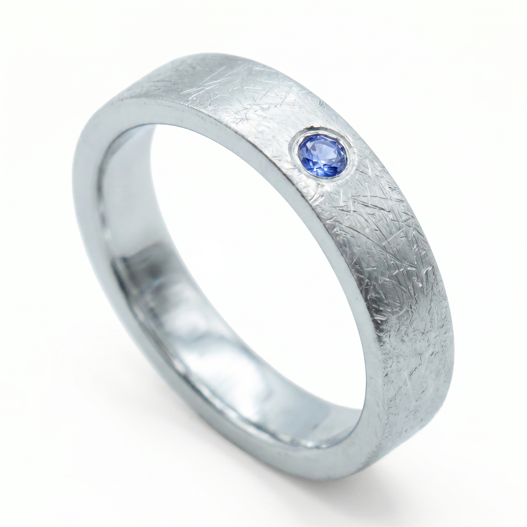 Close-up of sterling silver ring with blue topaz flush set stone and textured surface