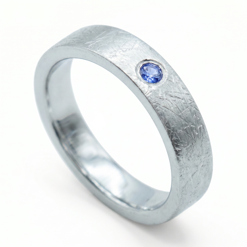 Close-up of sterling silver ring with blue topaz flush set stone and textured surface