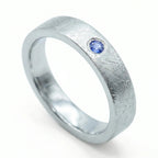 Close-up of sterling silver ring with blue topaz flush set stone and textured surface