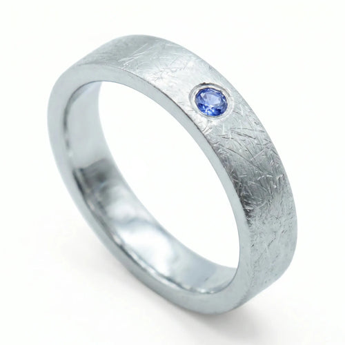 Close-up of sterling silver ring with blue topaz flush set stone and textured surface