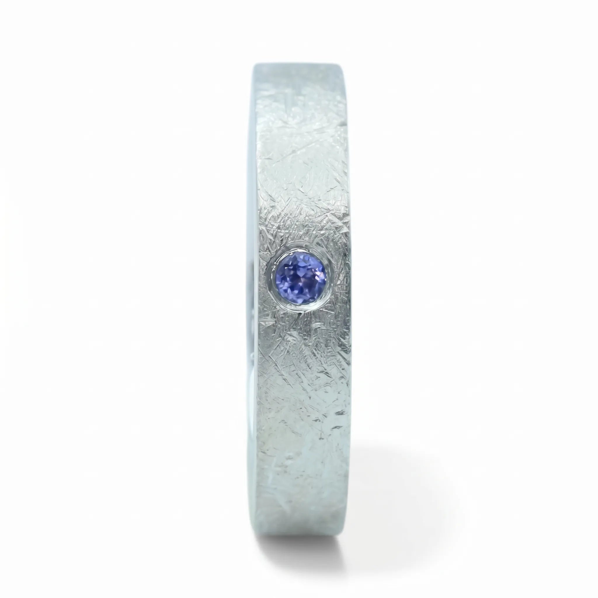 Close-up of sterling silver ring with blue topaz flush set stone and textured surface
