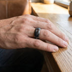 Cataclysm black titanium ring featuring meteorite fragments, blue dinosaur bone, lava stone inlay, and red glow accents with a rugged distressed finish.