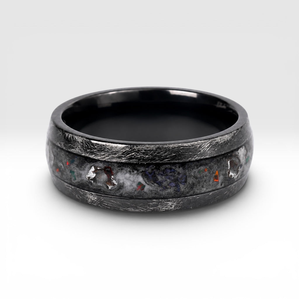 Cataclysm black titanium ring featuring meteorite fragments, blue dinosaur bone, lava stone inlay, and red glow accents with a rugged distressed finish.