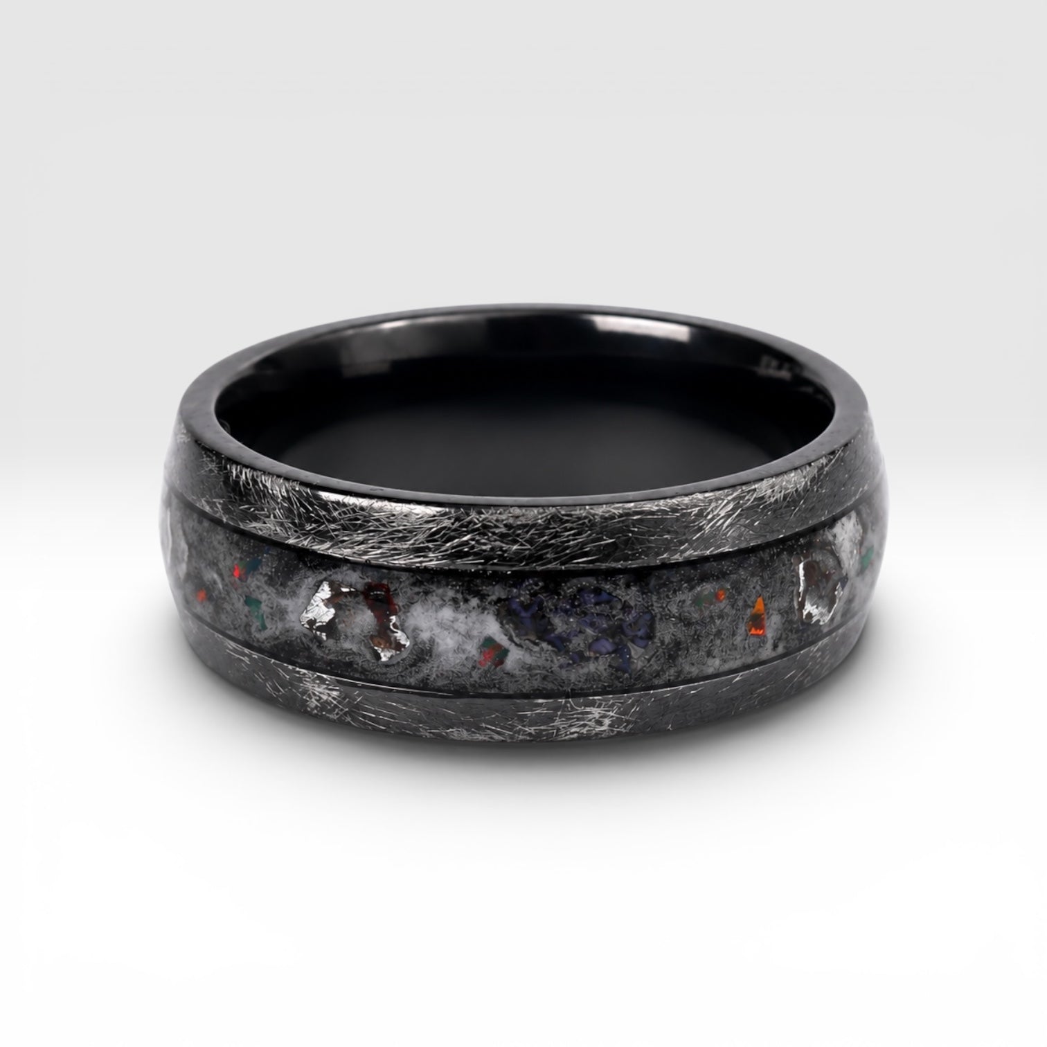 Cataclysm black titanium ring featuring meteorite fragments, blue dinosaur bone, lava stone inlay, and red glow accents with a rugged distressed finish.