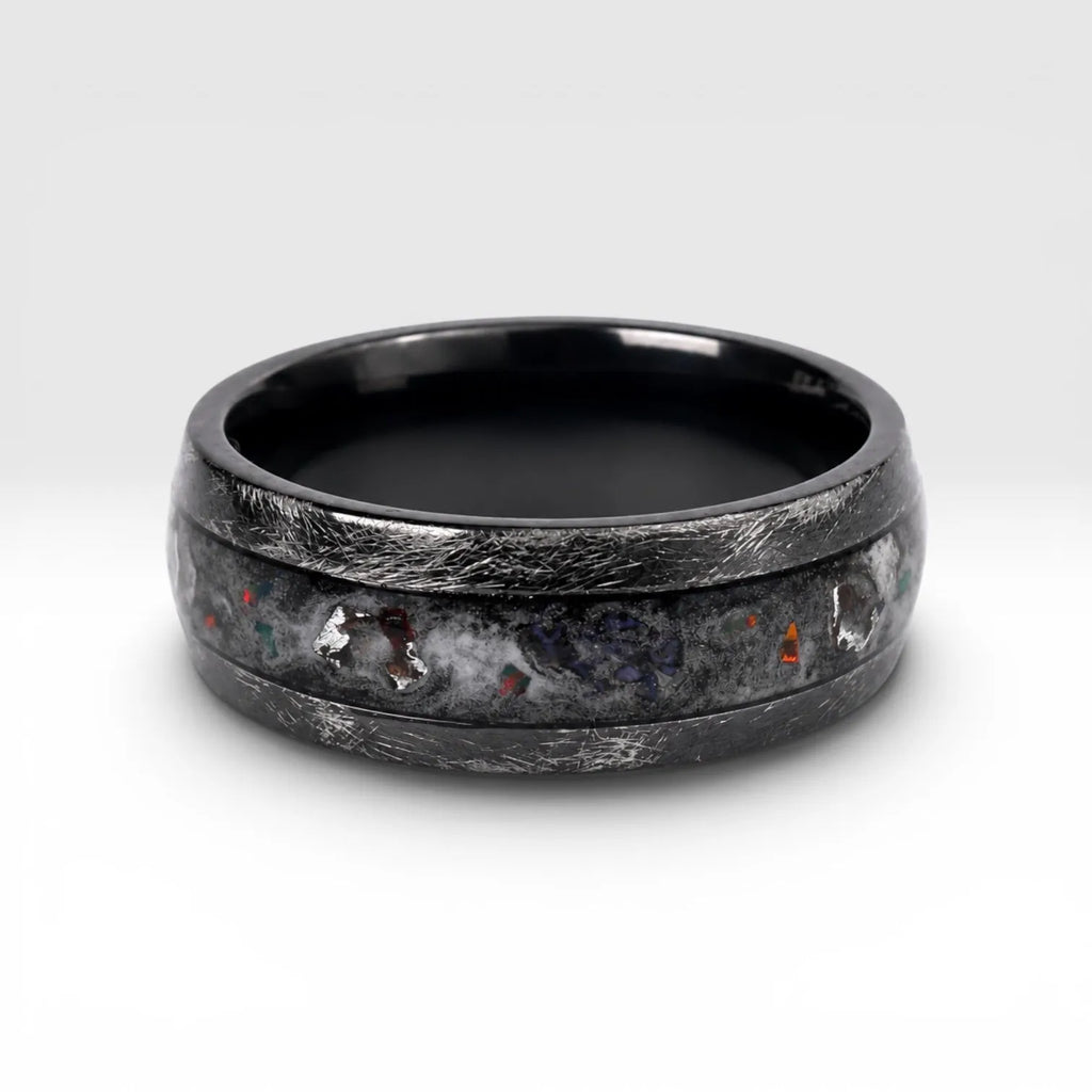 Cataclysm black titanium ring featuring meteorite fragments, blue dinosaur bone, lava stone inlay, and red glow accents with a rugged distressed finish.