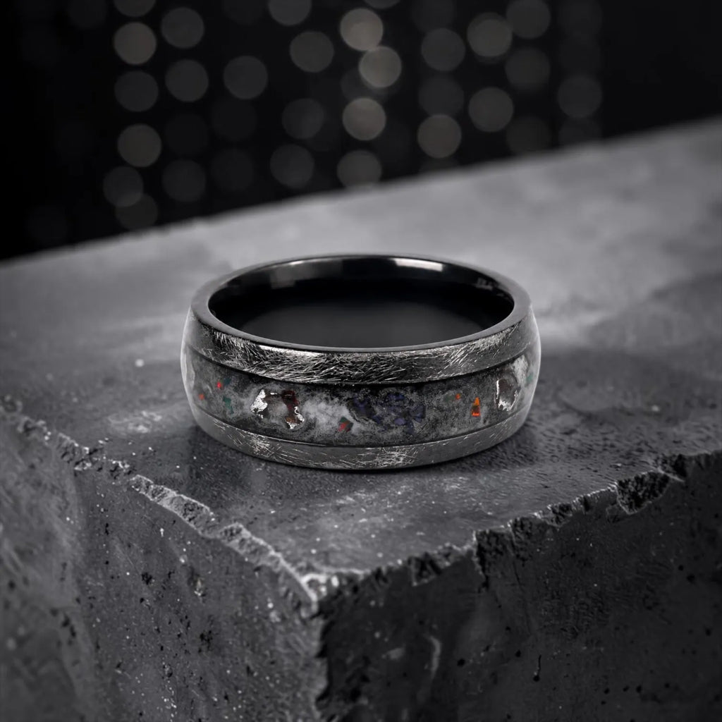 Cataclysm black titanium ring featuring meteorite fragments, blue dinosaur bone, lava stone inlay, and red glow accents with a rugged distressed finish.