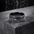 Cataclysm black titanium ring featuring meteorite fragments, blue dinosaur bone, lava stone inlay, and red glow accents with a rugged distressed finish.