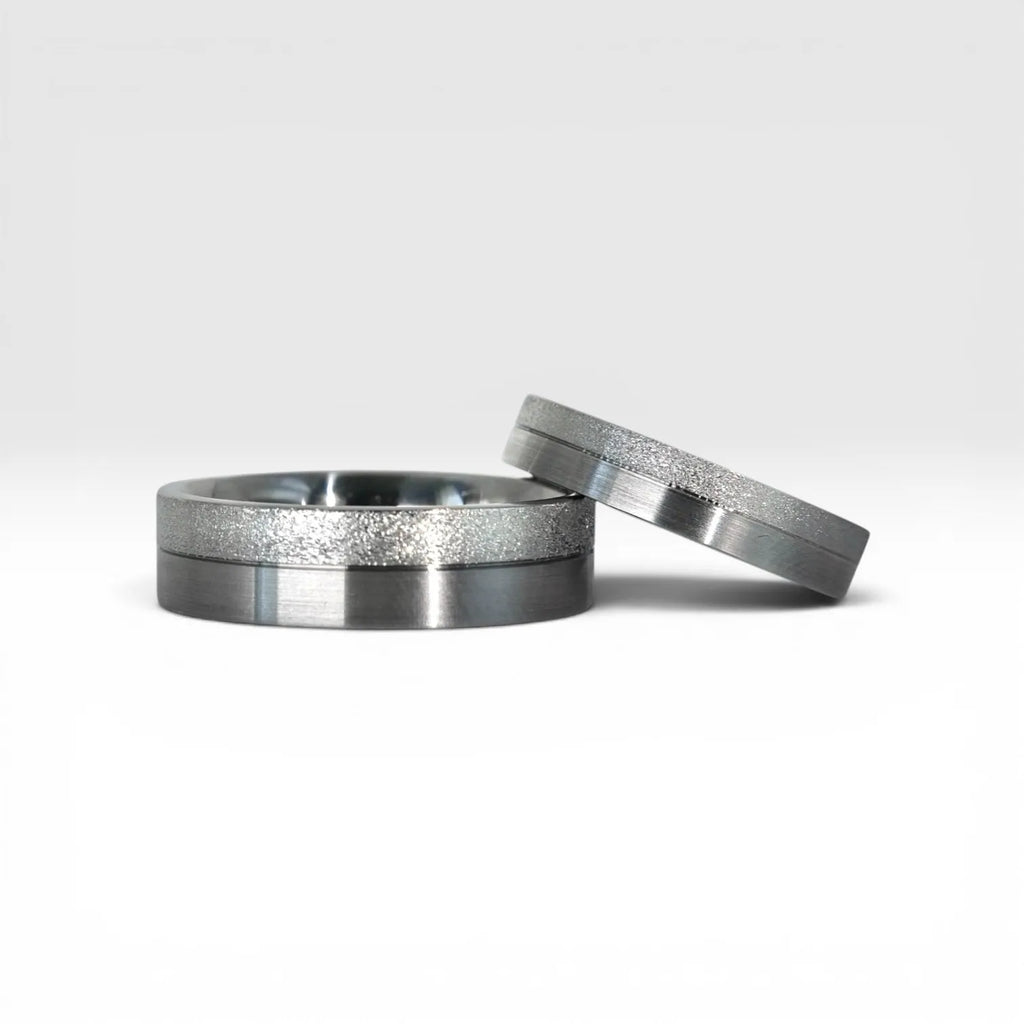Matching two-tone wedding band set, 6mm his and 4mm hers, with frosted diamond burr top half and satin lower half separated by a precision groove, handcrafted in Utah