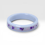 Forget Me Not white ceramic ring with real pressed flowers over a glow-in-the-dark background, handcrafted memorial jewelry