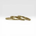 Órbita stack set — three gold stacking rings with different handcrafted finishes laid out for mix and match styling
