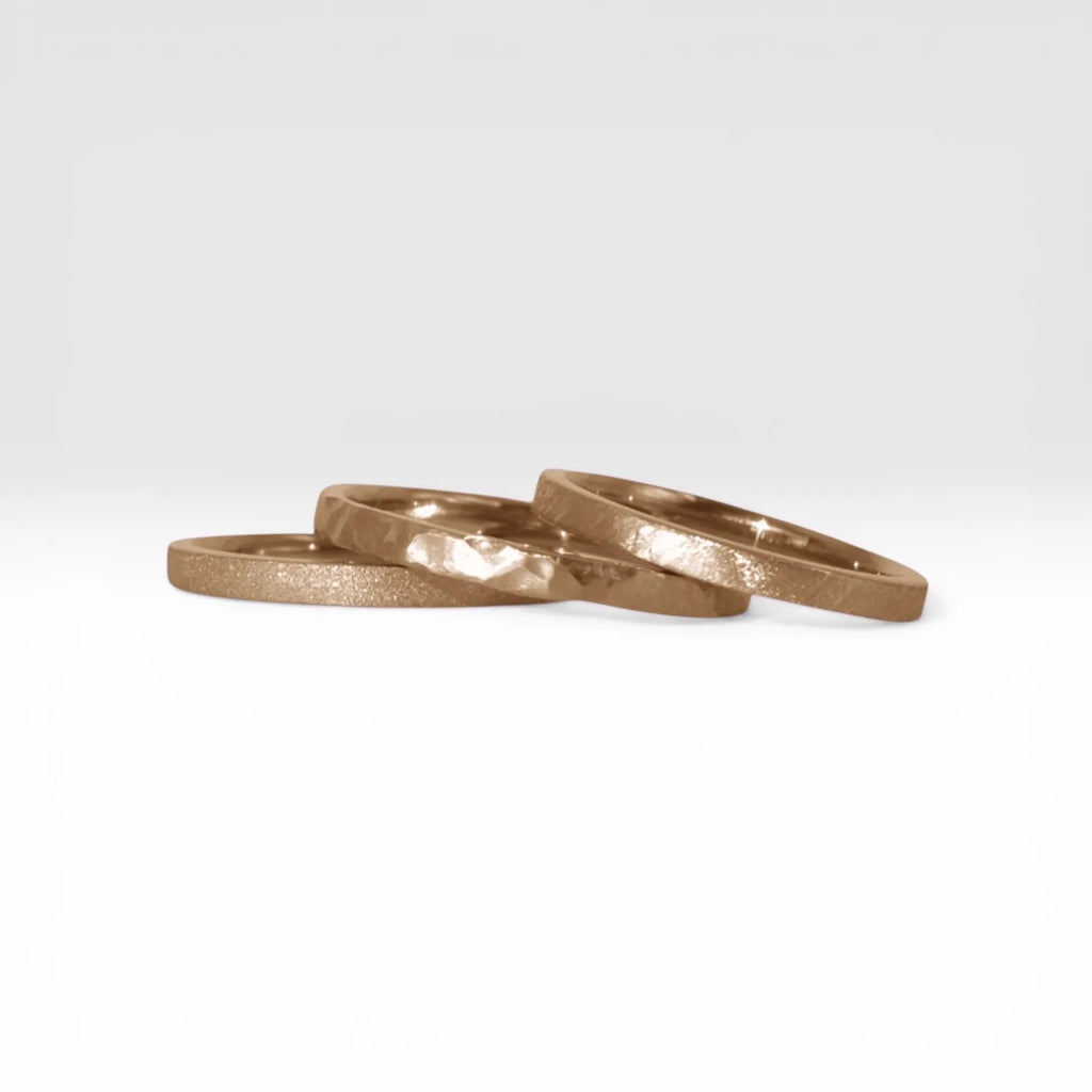 Órbita stack set — three rose gold stacking rings with different handcrafted finishes laid out for mix and match styling