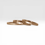 Órbita stack set — three rose gold stacking rings with different handcrafted finishes laid out for mix and match styling