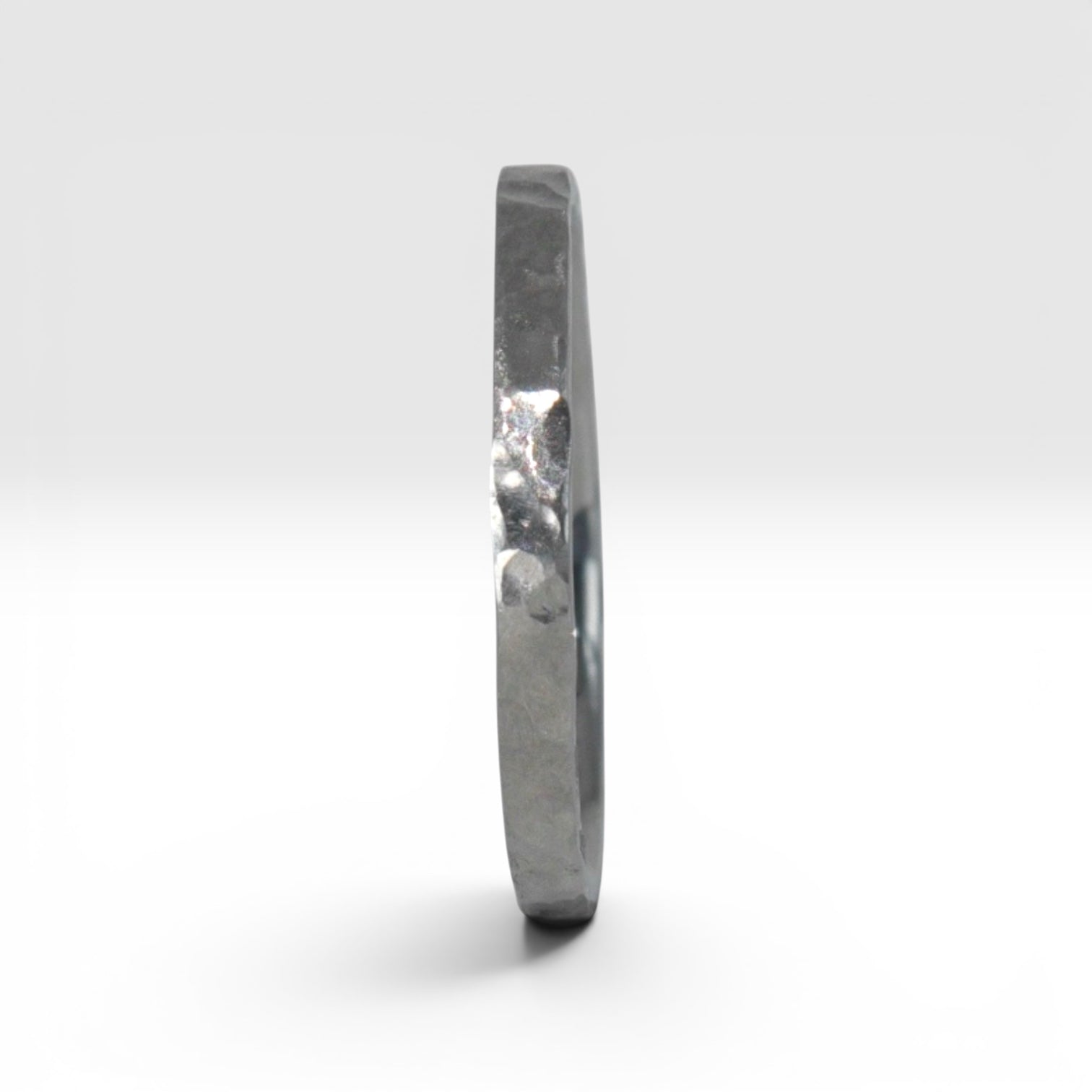 Side view of Órbita Roca hammered titanium stacking ring showing raw textured surface and slim 2mm profile