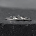 Órbita stack set — three titanium stacking rings with different handcrafted finishes laid out for mix and match styling