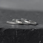 Órbita stack set — three titanium stacking rings with different handcrafted finishes laid out for mix and match styling
