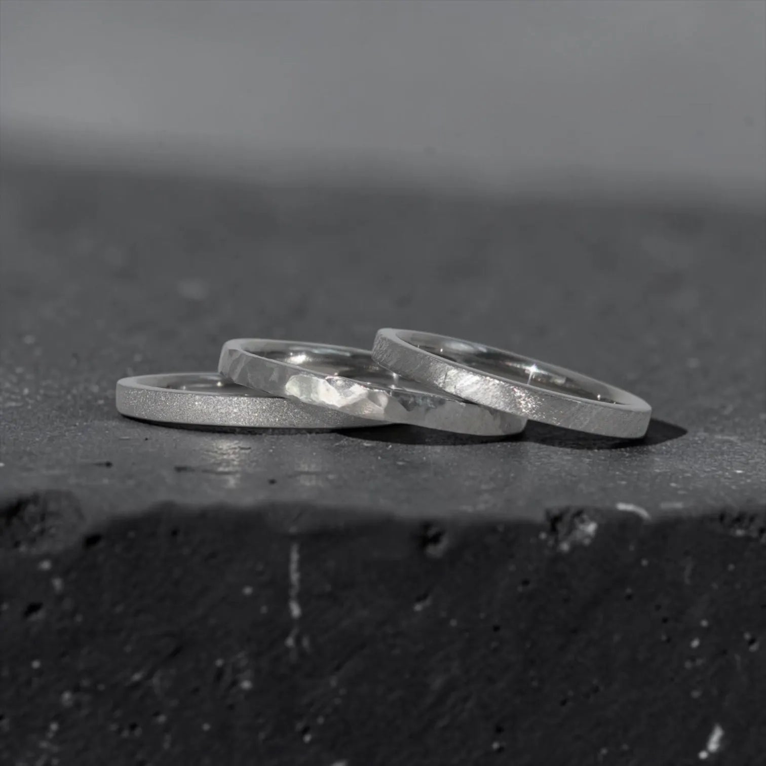 Órbita stack set — three titanium stacking rings with different handcrafted finishes laid out for mix and match styling