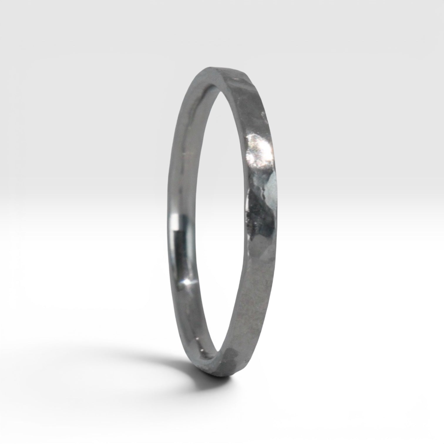 Side view of Órbita Roca hammered titanium stacking ring showing raw textured surface and slim 2mm profile