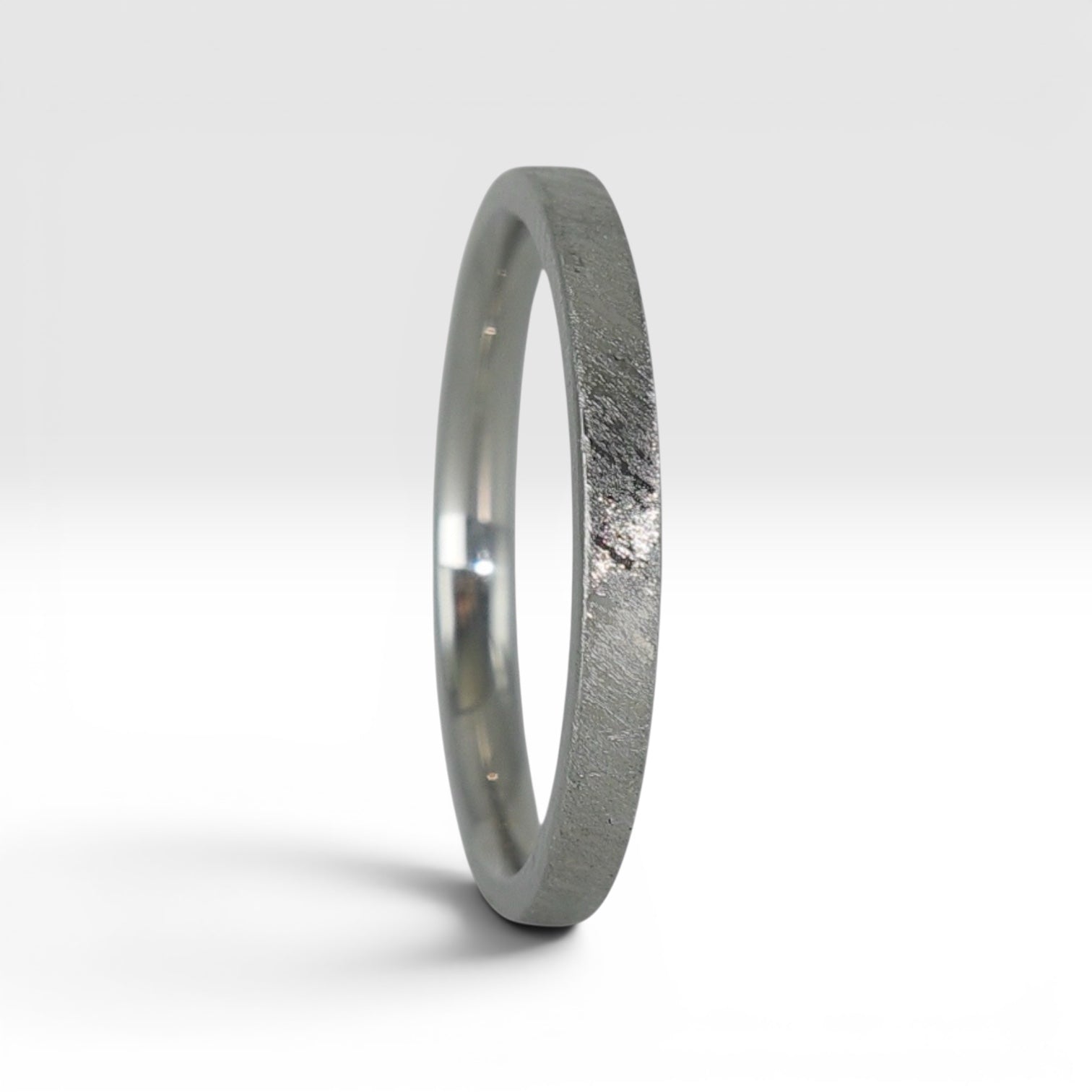 Side view of Órbita Corte diagonal texture titanium stacking ring showing unique angled finish and slim 2mm profile