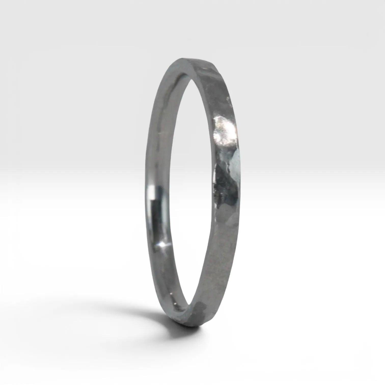 Side view of Órbita Roca hammered stacking ring showing raw textured surface and slim 2mm profile