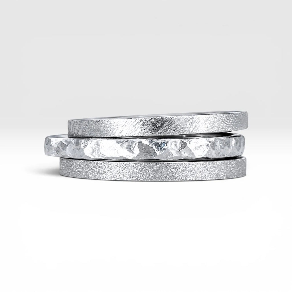 Órbita collection — three 2mm sterling silver stackable rings stacked together showing hammered, frosted, and diagonal textures, handcrafted in Utah