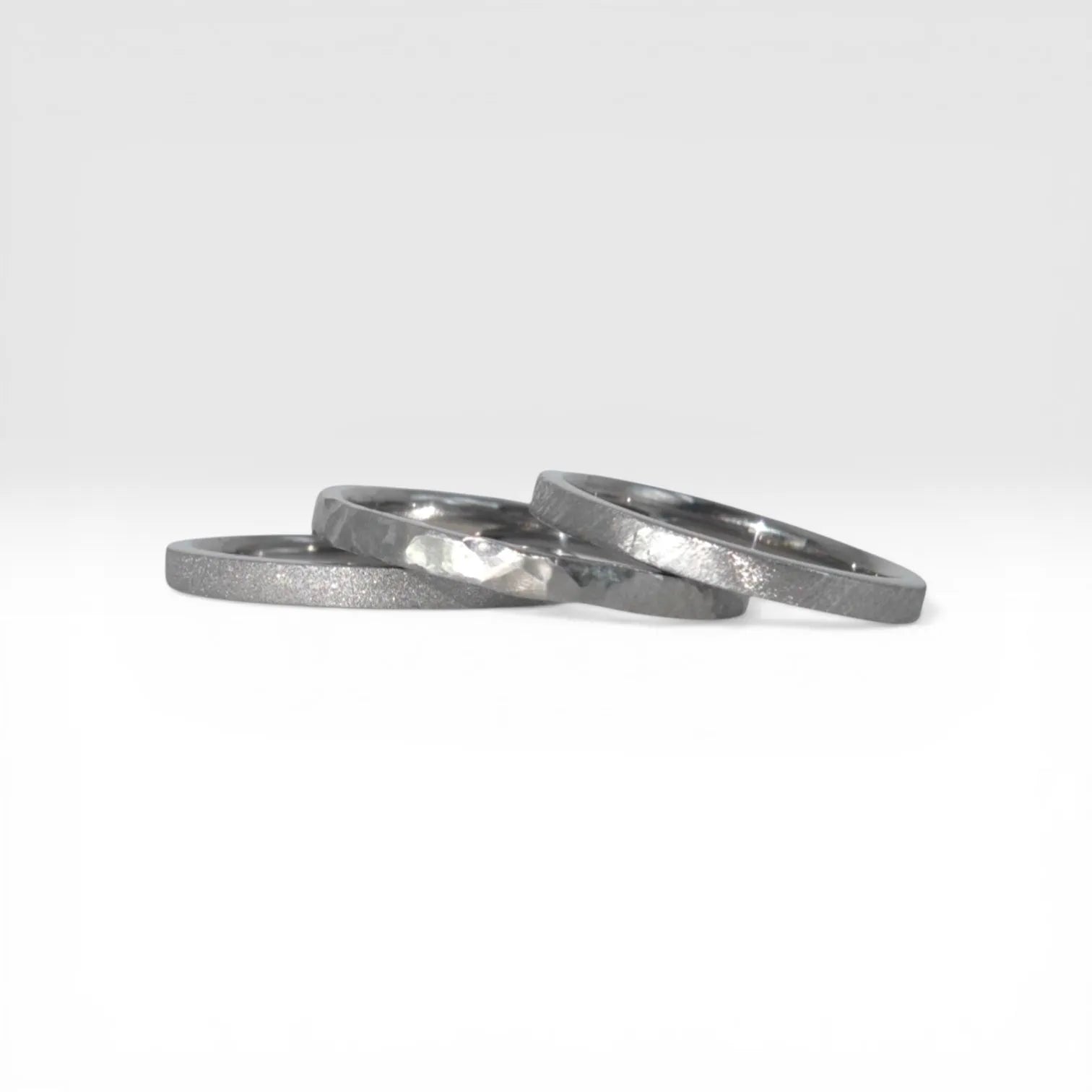 Three titanium stackable rings stacked together showing hammered, frosted, and diagonal textures, 2mm width, handcrafted in Utah