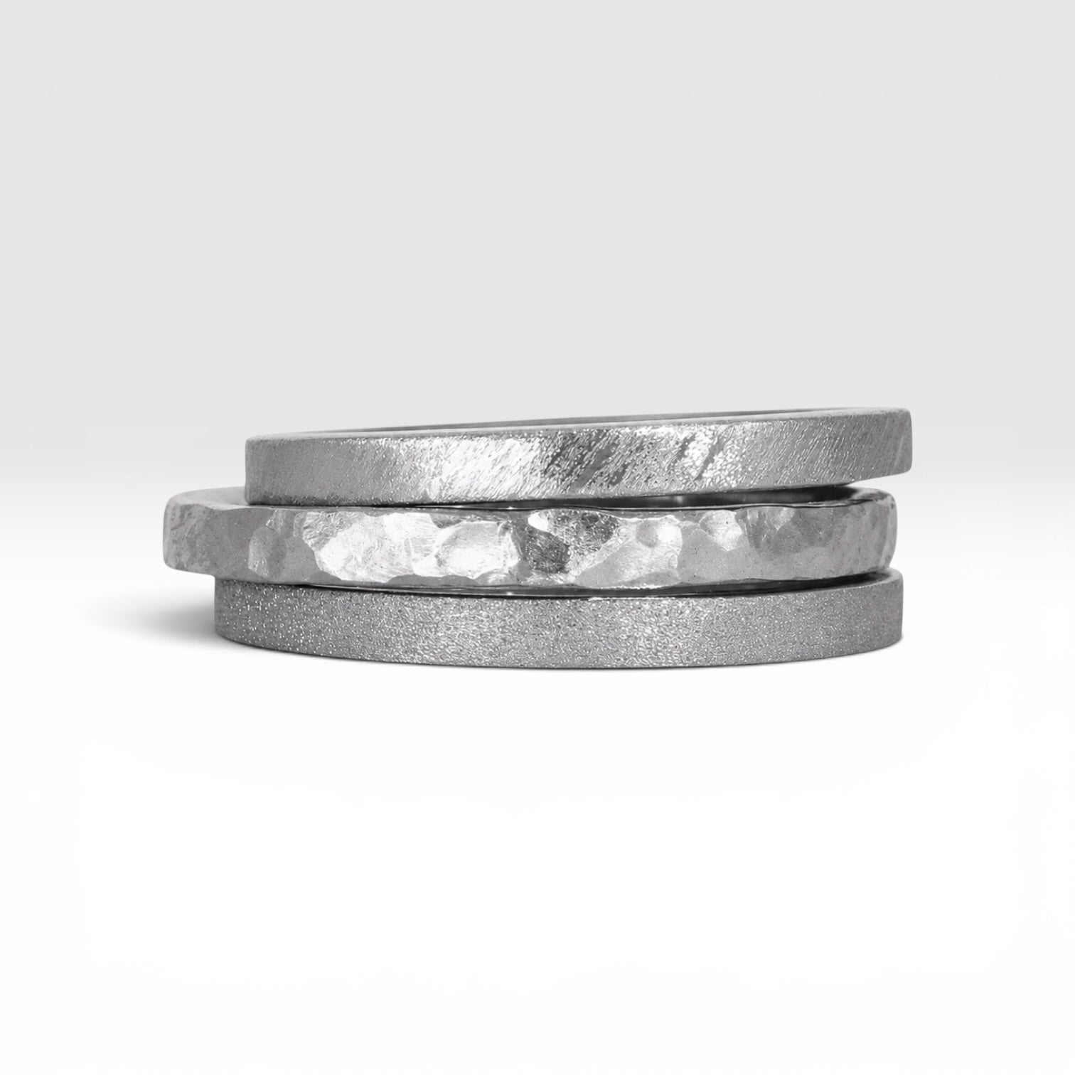 Three titanium stackable rings stacked together showing hammered, frosted, and diagonal textures, 2mm width, handcrafted in Utah