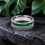 Close-up of titanium ring with paua shell inlay showing iridescent blue, green, and purple tones