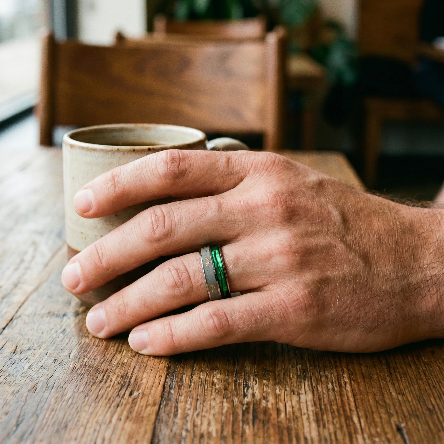 Titanium paua shell ring worn on hand with vibrant iridescent finish