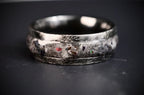 Cataclysm black titanium ring featuring meteorite fragments, blue dinosaur bone, lava stone inlay, and red glow accents with a rugged distressed finish.