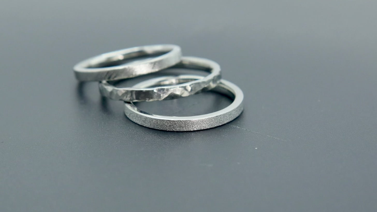 Órbita stack set — three titanium stacking rings with different handcrafted finishes laid out for mix and match styling