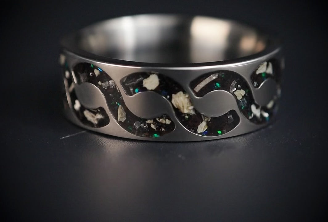 Abyssforge titanium ring featuring Megalodon tooth fragments, Campo del Cielo meteorite shavings, Mount Etna lava stone, green opal accents, and a sculpted flowing pattern.