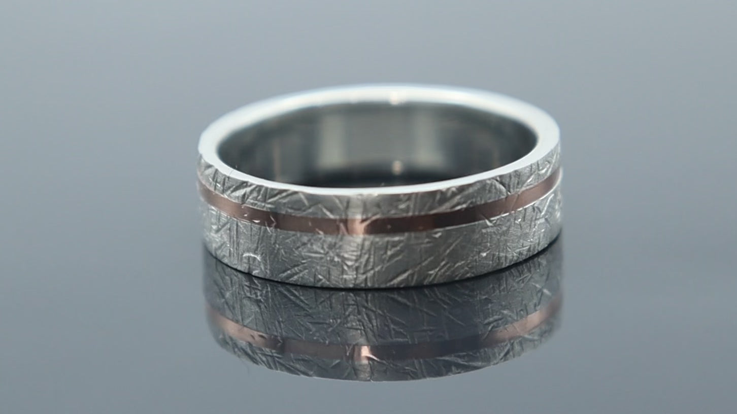 Silver ring with meteorite inspired texture and fine rose gold line creating depth and contrast
