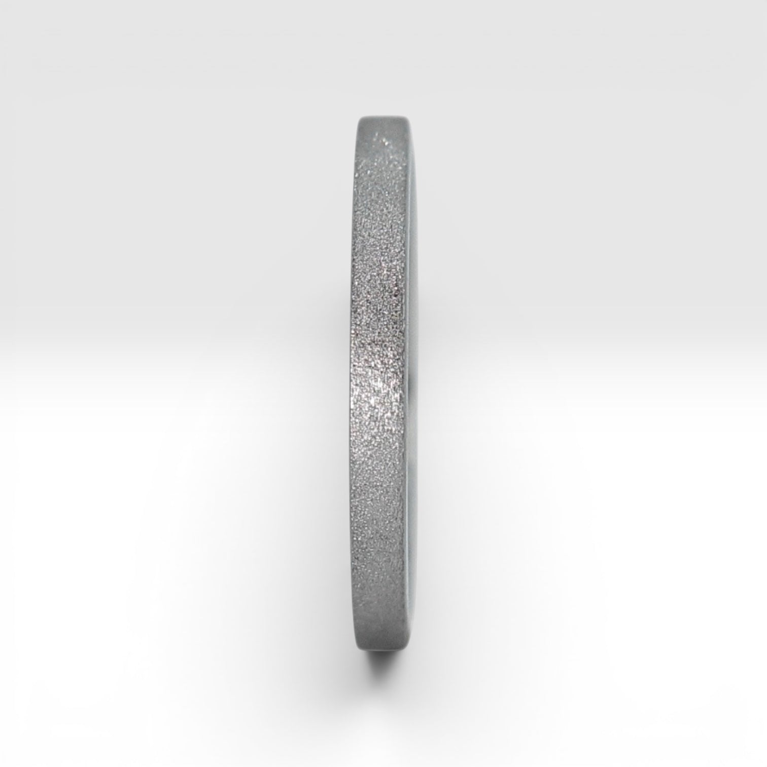 Upright view of órbita luz frosted titanium stacking ring showing fine sparkle texture and polished interior