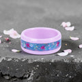 Skyblossom pink ceramic ring featuring preserved blue flower petals, pink pressed flowers, and iridescent accents in a handcrafted floral inlay.