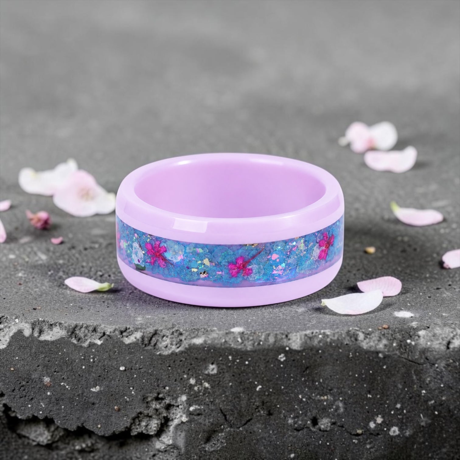 Skyblossom pink ceramic ring featuring preserved blue flower petals, pink pressed flowers, and iridescent accents in a handcrafted floral inlay.