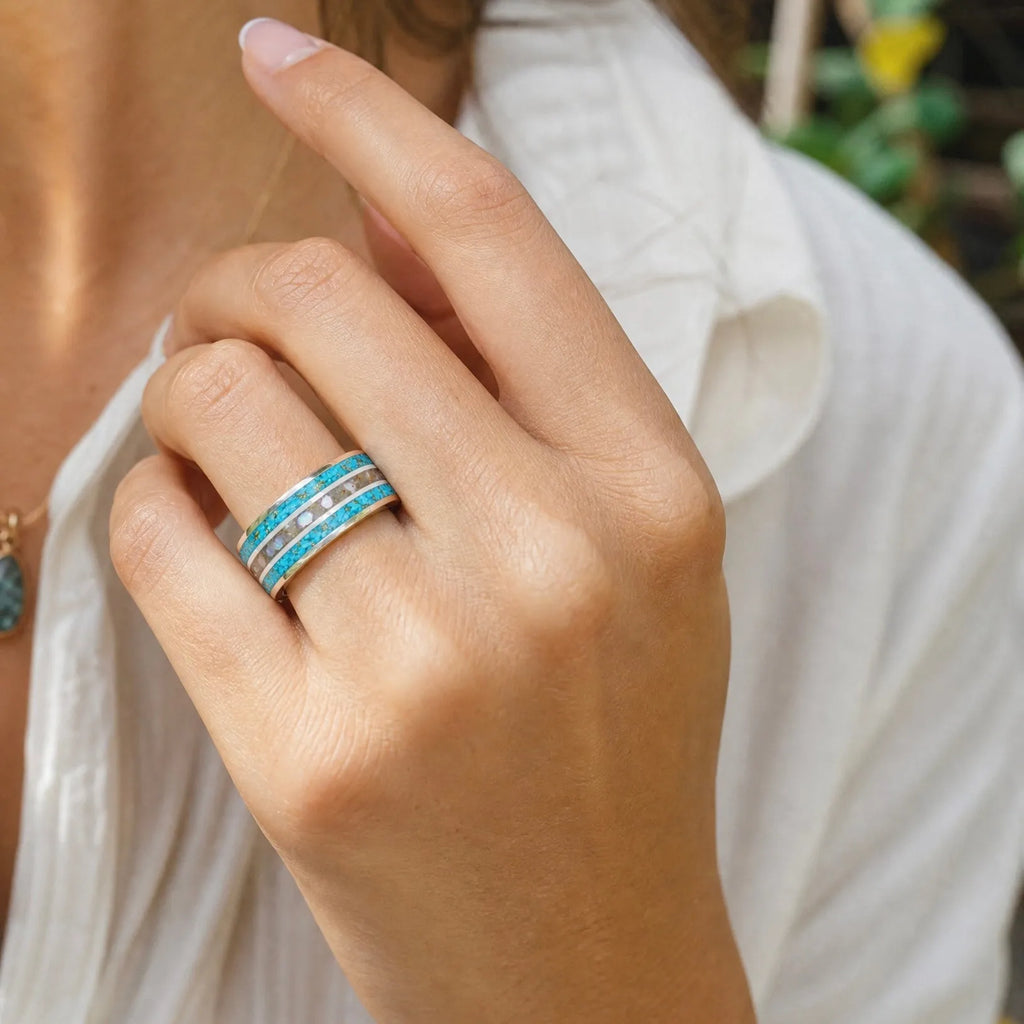 Close-up of tungsten ring with turquoise, mother of pearl and gold leaf showing layered ocean inspired inlay