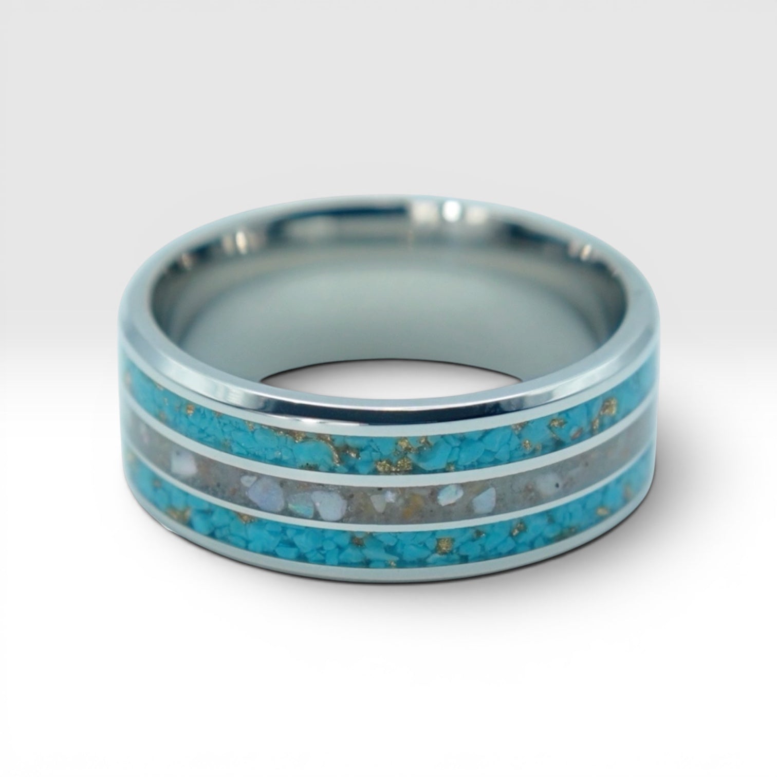 Close-up of tungsten ring with turquoise, mother of pearl and gold leaf showing layered ocean inspired inlay