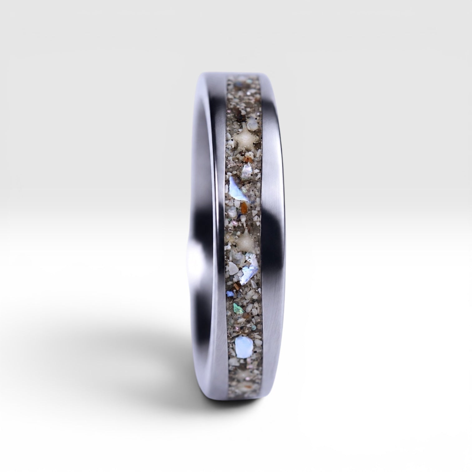 Stellatide titanium ring featuring Bermuda beach sand, Okinawa star sand, and mother of pearl inlay handcrafted by Venus Rings.