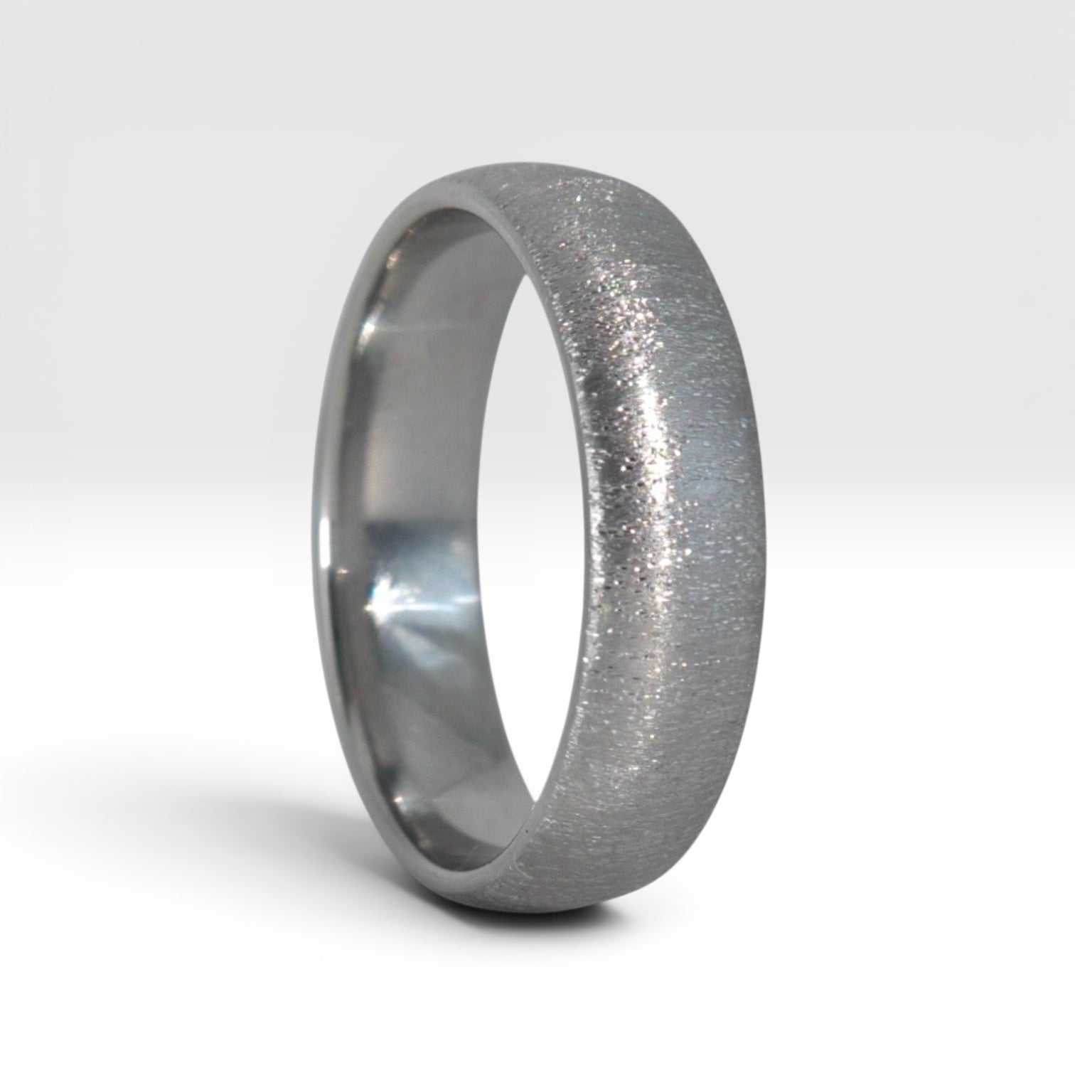  4mm domed titanium women's wedding band with fine vertical texture creating a luminous sparkle effect