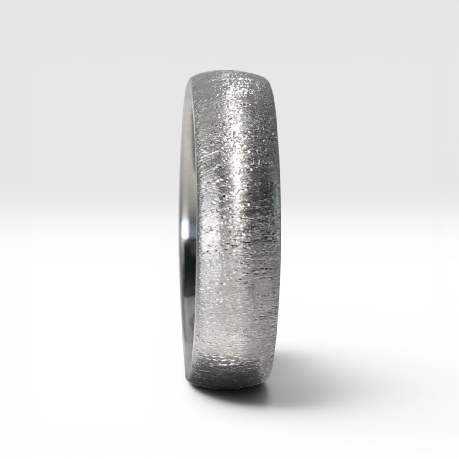 4mm domed titanium women's wedding band with fine vertical texture creating a luminous sparkle effect