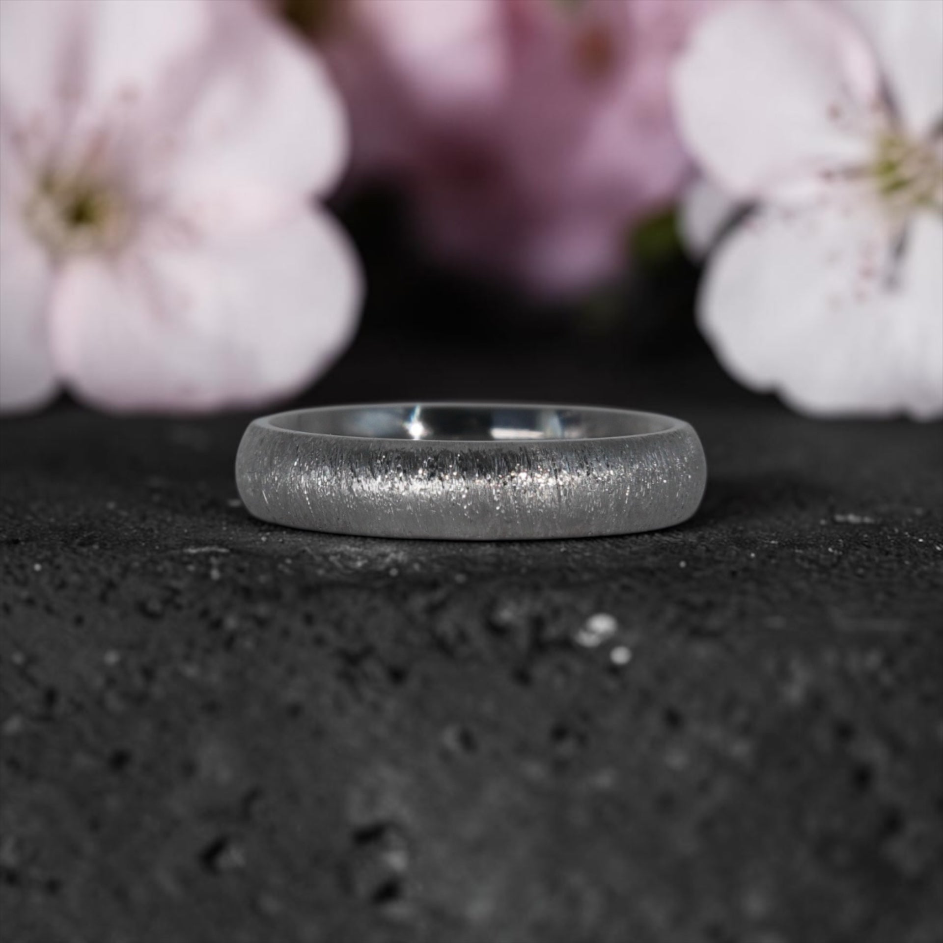 4mm domed titanium women's wedding band with fine vertical texture creating a luminous sparkle effect