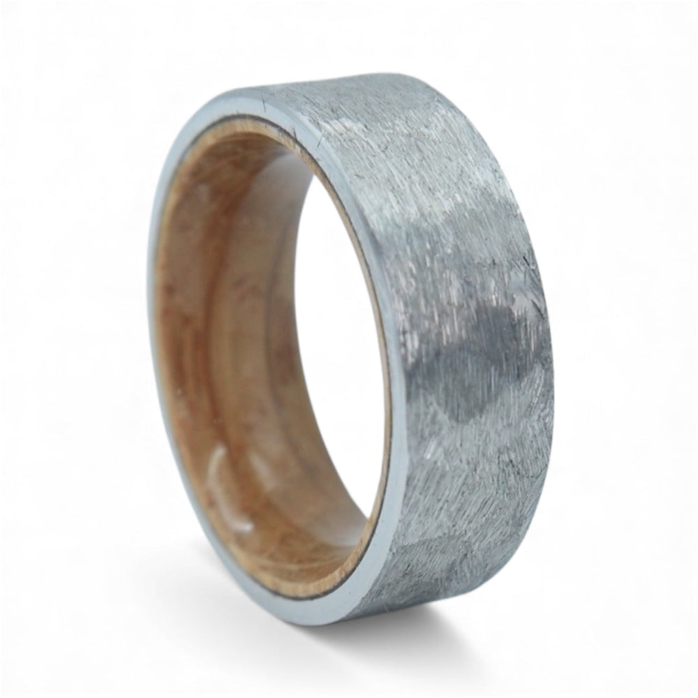 Close-up of tungsten ring with whiskey barrel wood interior showing natural grain and rustic forged texture